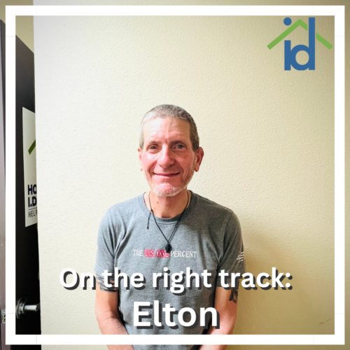 a man with short greying hair with a grey tee shirt and the words 'on the right track: Elton' and a homeless id project logo in the top corner with a white border